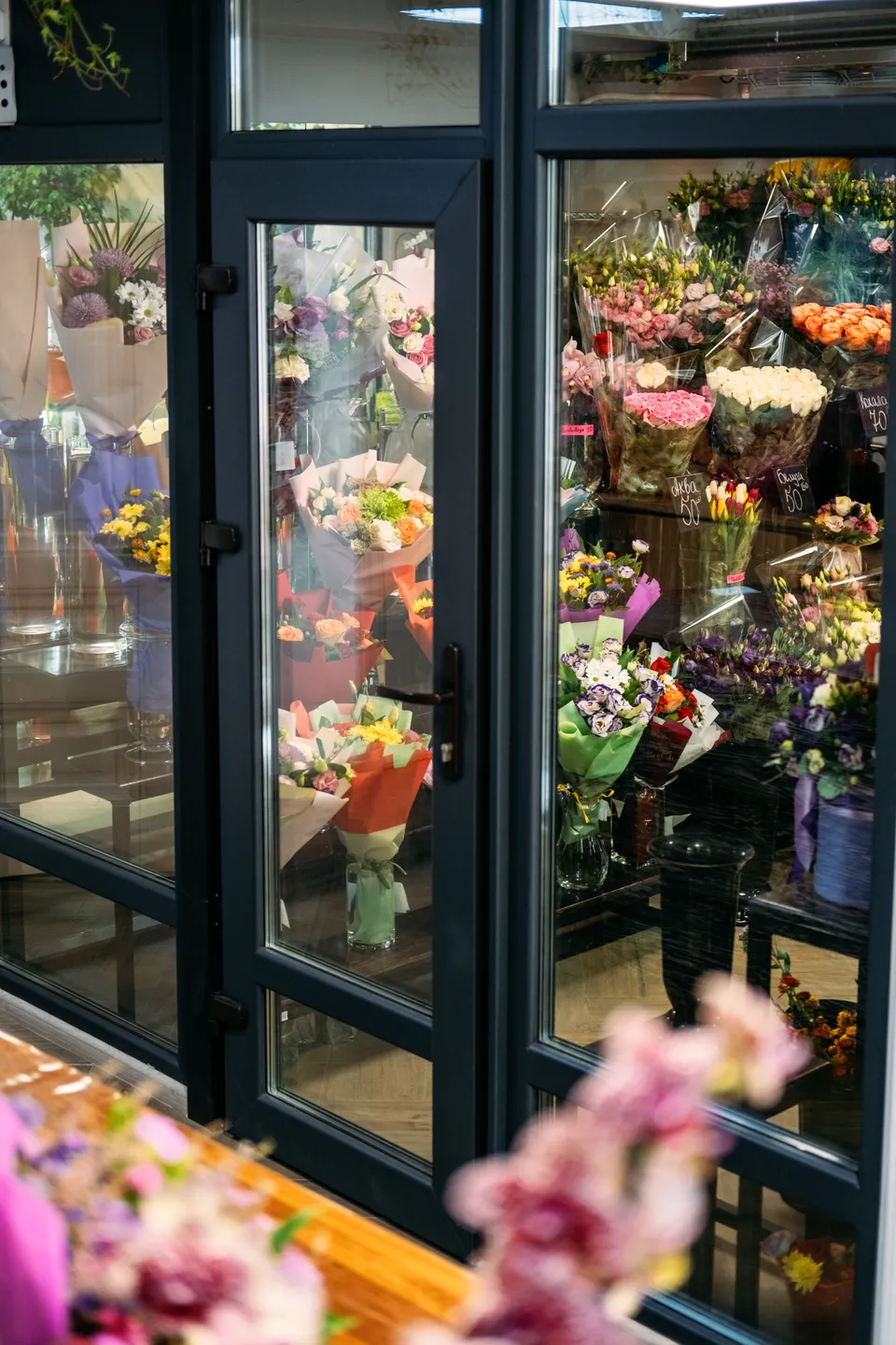 Colorful flower displays visible through a shop’s glass doors and windows